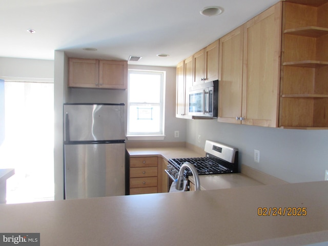 kitchen featuring stainless steel appliances, light brown cabinetry, open shelves, and light countertops