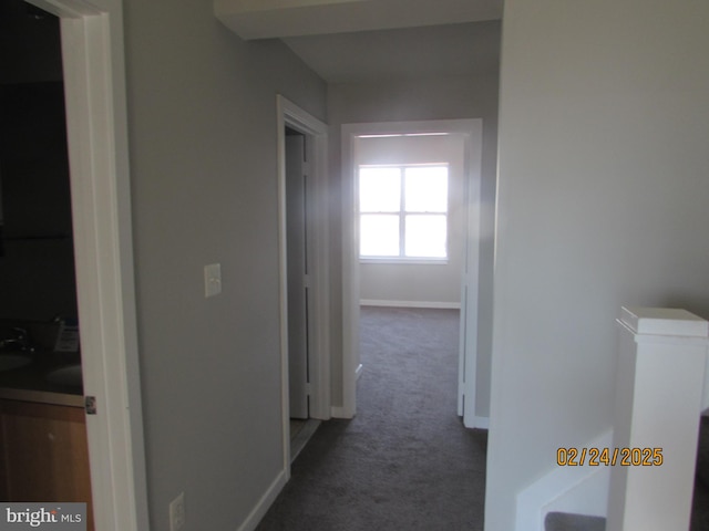 hallway featuring an upstairs landing, carpet, and baseboards