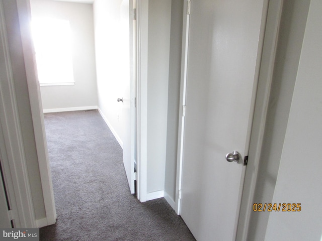 hallway with baseboards and dark carpet