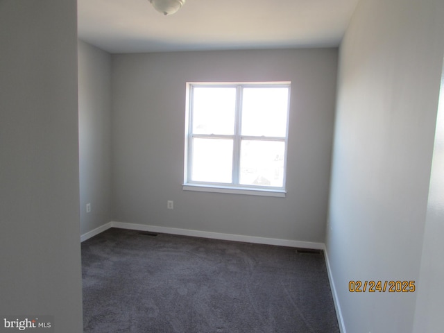 spare room with dark carpet and baseboards