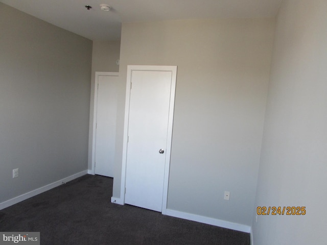 unfurnished bedroom featuring baseboards and dark colored carpet