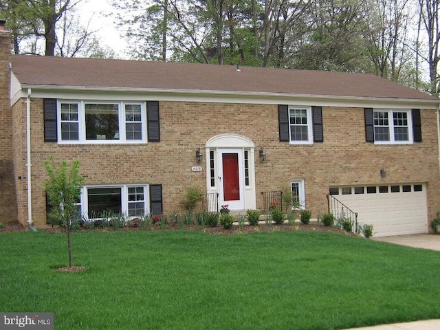 split foyer home with a garage, brick siding, concrete driveway, and a front yard