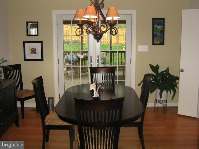 dining space featuring a notable chandelier, baseboards, and wood finished floors