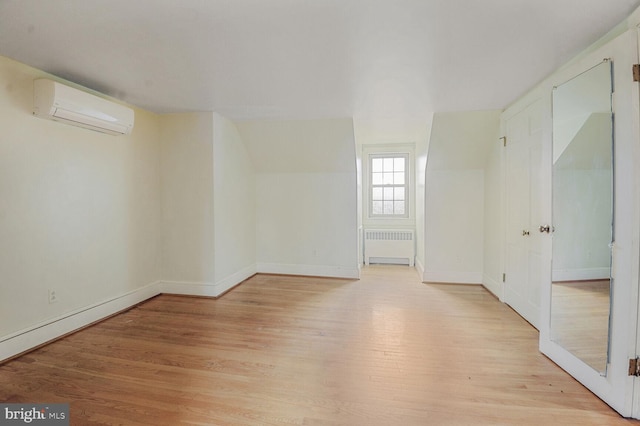 unfurnished room featuring light wood-style floors, radiator, a wall mounted air conditioner, and baseboards