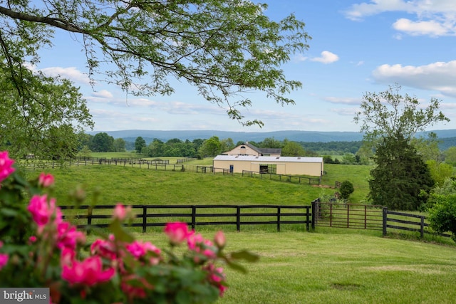 view of yard featuring an outbuilding, a rural view, fence, a pole building, and a mountain view