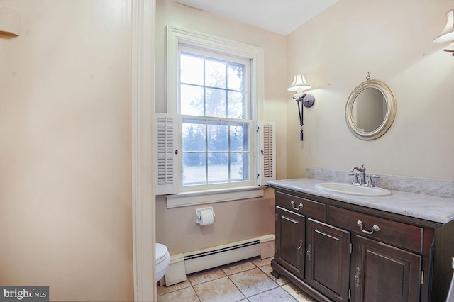 bathroom with toilet, vanity, a baseboard heating unit, and tile patterned floors