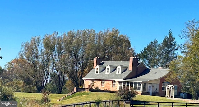 view of front facade featuring a chimney, a front yard, and fence