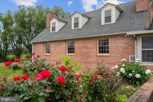 view of side of property featuring brick siding, a chimney, and roof with shingles