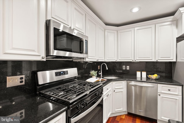 kitchen featuring appliances with stainless steel finishes, white cabinetry, and a sink