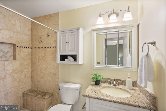 bathroom featuring tiled shower, vanity, and toilet