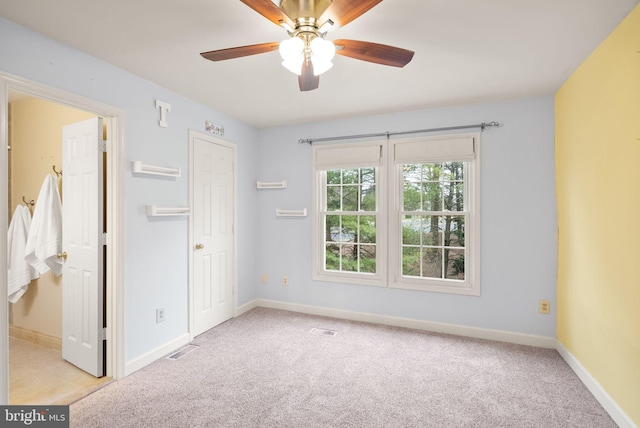 empty room featuring carpet floors, visible vents, baseboards, and a ceiling fan