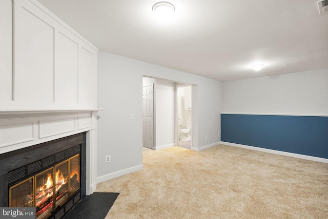 unfurnished living room with carpet, a fireplace with flush hearth, visible vents, and baseboards