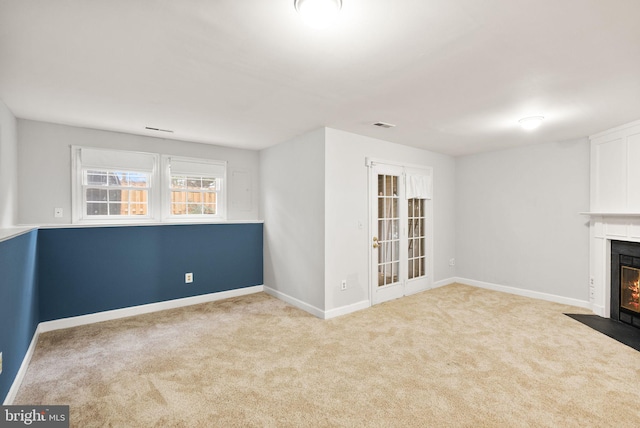 unfurnished living room featuring a fireplace with flush hearth, visible vents, carpet floors, and baseboards