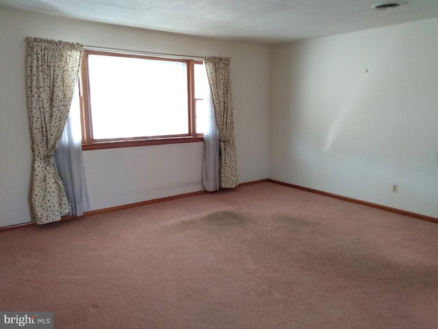 carpeted spare room featuring visible vents and baseboards