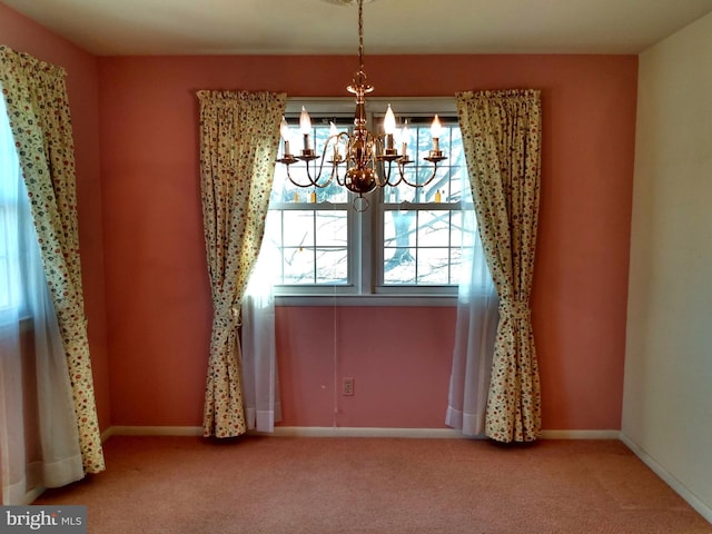 unfurnished dining area with baseboards, carpet floors, and an inviting chandelier