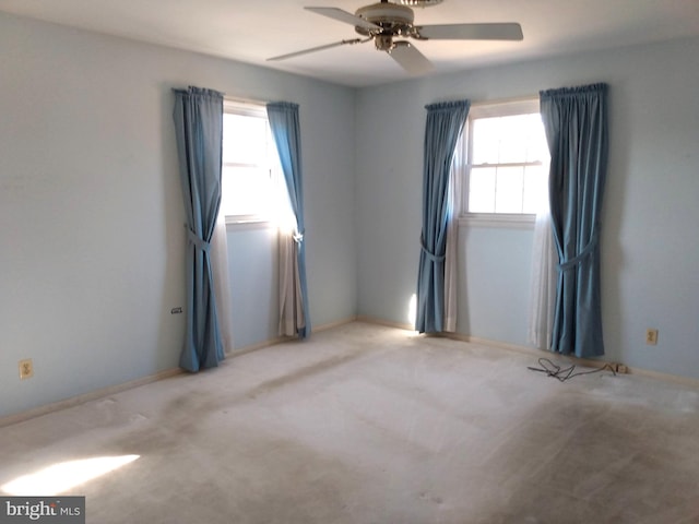 carpeted empty room featuring a ceiling fan, a wealth of natural light, and baseboards