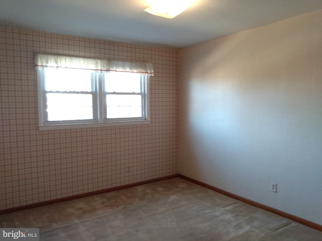 carpeted empty room featuring baseboards