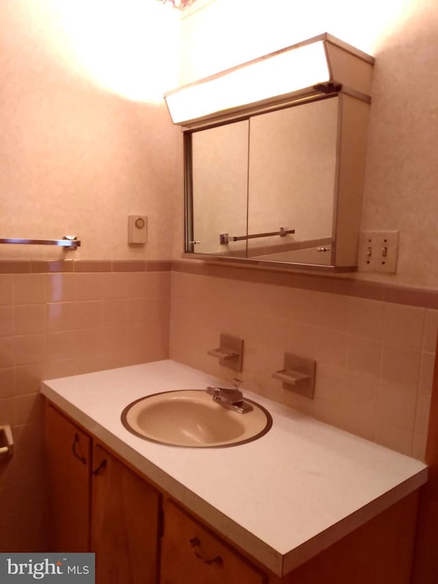 bathroom with a wainscoted wall, vanity, and tile walls