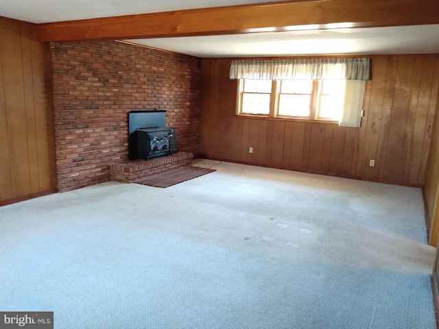 unfurnished living room with a wood stove, wood walls, and beamed ceiling