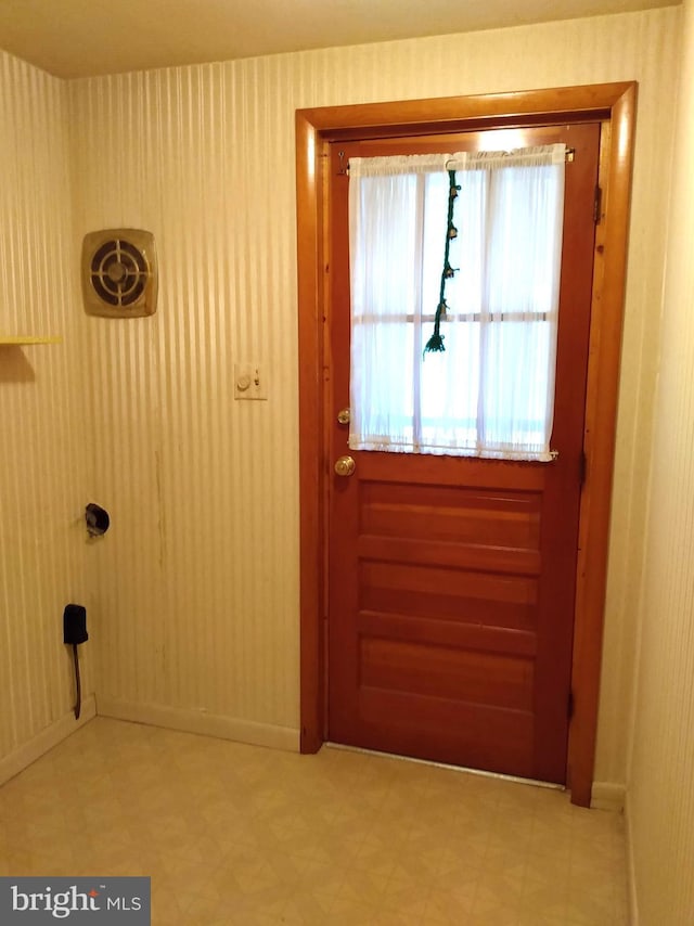 entryway featuring baseboards, light floors, and wallpapered walls