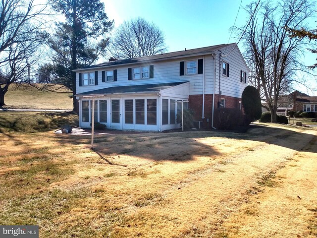 back of house with a sunroom, brick siding, and a chimney