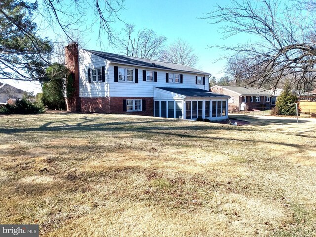 view of front facade featuring a front lawn, a chimney, and a sunroom