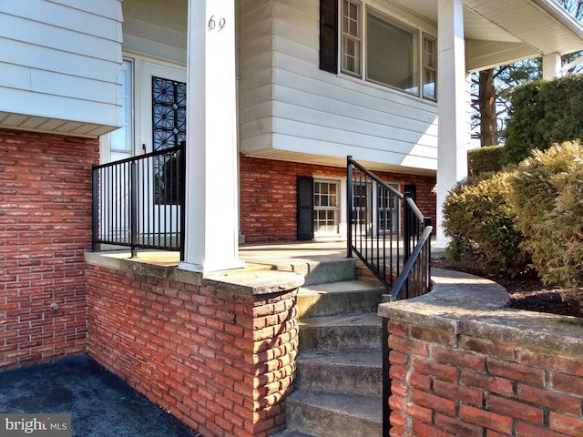 entrance to property featuring a porch and brick siding