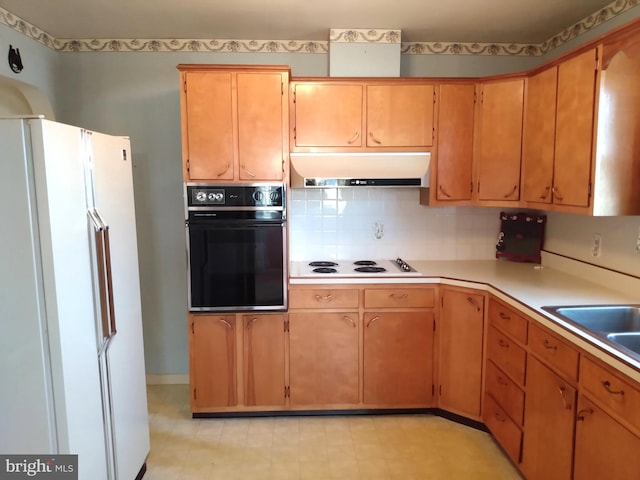 kitchen with under cabinet range hood, white appliances, a sink, light countertops, and tasteful backsplash