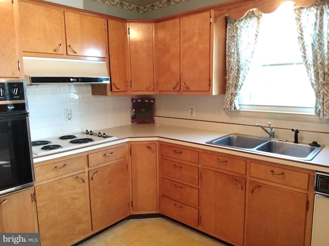 kitchen with under cabinet range hood, a sink, black oven, light countertops, and white electric stovetop