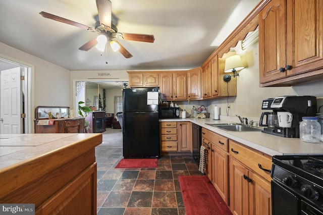 kitchen with tile counters, a ceiling fan, stone finish flooring, black appliances, and a sink