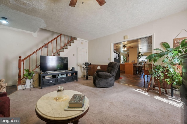 carpeted living room with ceiling fan, stairway, and a textured ceiling