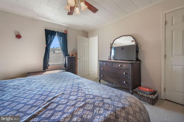 carpeted bedroom with a ceiling fan and crown molding