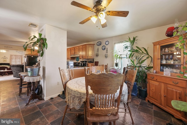 dining area with ceiling fan, stone tile flooring, visible vents, and baseboards