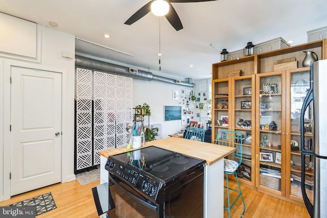 kitchen with black / electric stove, butcher block counters, freestanding refrigerator, and light wood-style floors