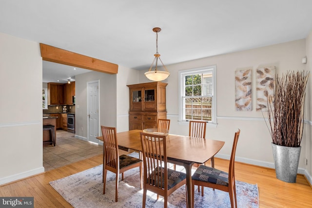 dining area with baseboards and light wood-style flooring