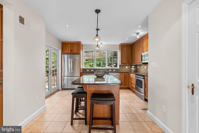 kitchen with decorative backsplash, light tile patterned floors, visible vents, and stainless steel appliances