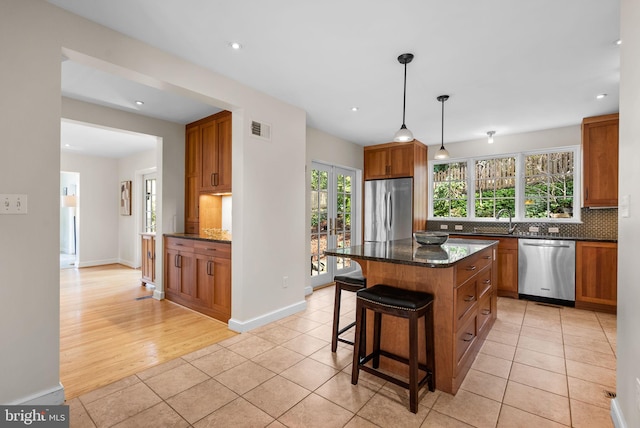 kitchen featuring visible vents, a sink, decorative backsplash, french doors, and appliances with stainless steel finishes