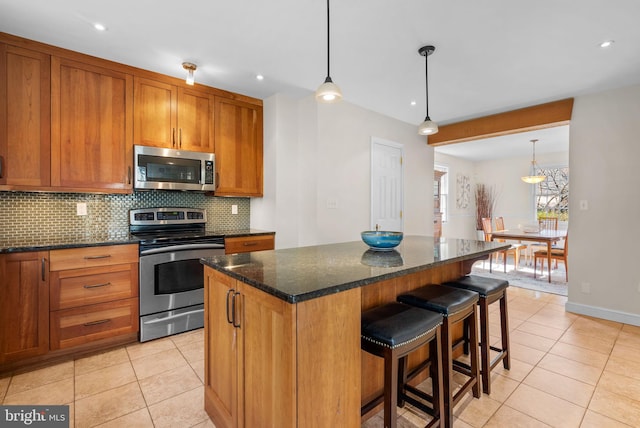 kitchen with light tile patterned floors, brown cabinets, backsplash, and appliances with stainless steel finishes