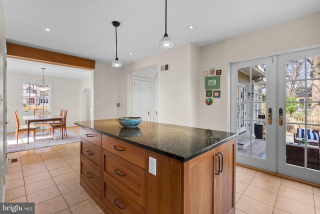 kitchen with light tile patterned floors, visible vents, arched walkways, and brown cabinetry