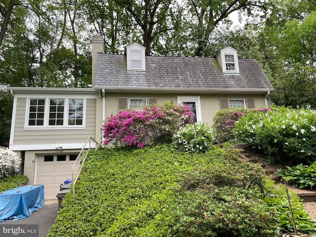 cape cod-style house with a garage, brick siding, and a chimney