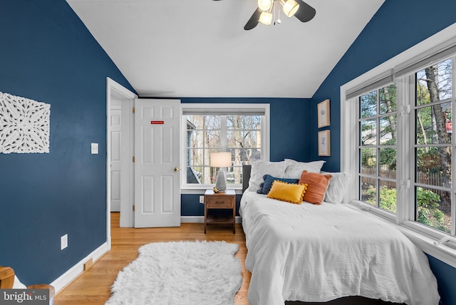 bedroom featuring vaulted ceiling, multiple windows, and wood finished floors