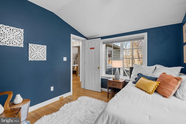 bedroom with baseboards, lofted ceiling, and wood finished floors