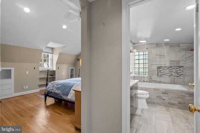 bedroom featuring vaulted ceiling, multiple windows, wood finished floors, and baseboards