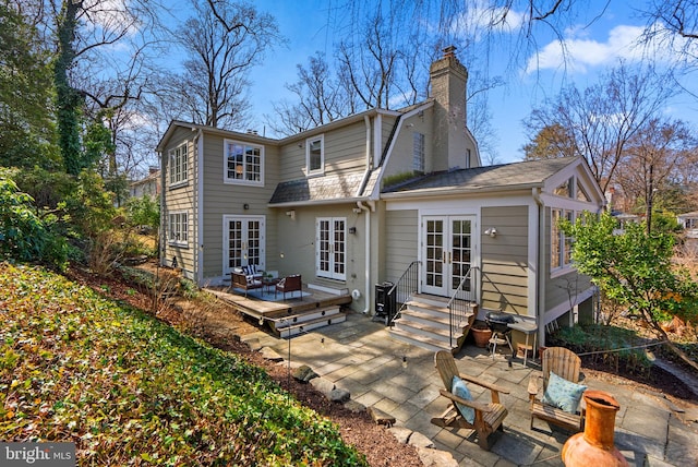 back of house featuring a gambrel roof, a deck, entry steps, a patio, and french doors