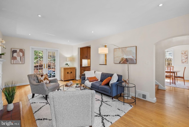 living area with arched walkways, visible vents, light wood-style flooring, and recessed lighting