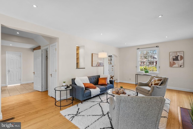 living area with recessed lighting, light wood-type flooring, and arched walkways