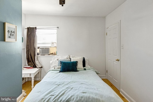 bedroom with wood finished floors, cooling unit, and baseboards