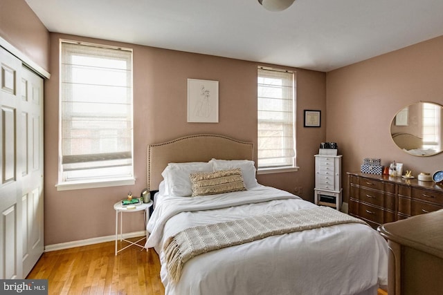 bedroom featuring multiple windows, light wood-style flooring, and baseboards