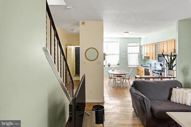 living area with baseboards, stairway, and light wood finished floors