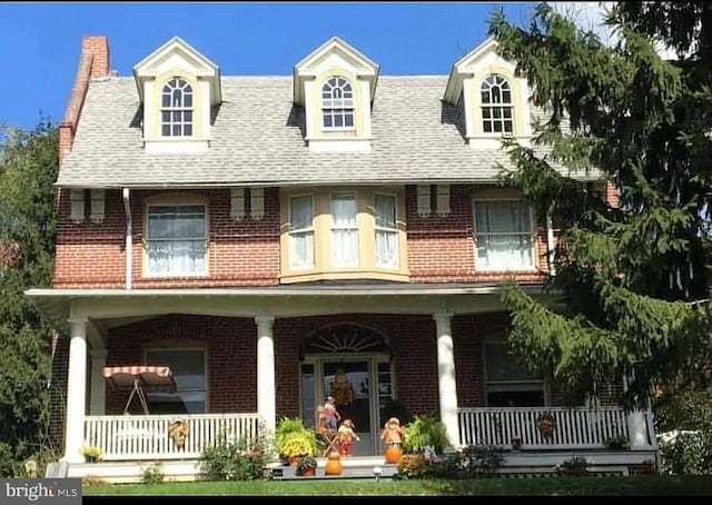 rear view of property with brick siding and a porch